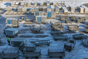 Containers with trolleys in the storage area at the winter airport.