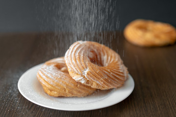 process of sprinkling donuts with powdered sugar