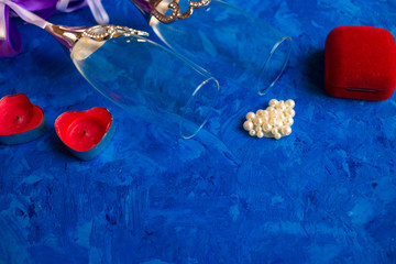 Champagne glasses on a blue background with a box for a ring on Valentine's Day
