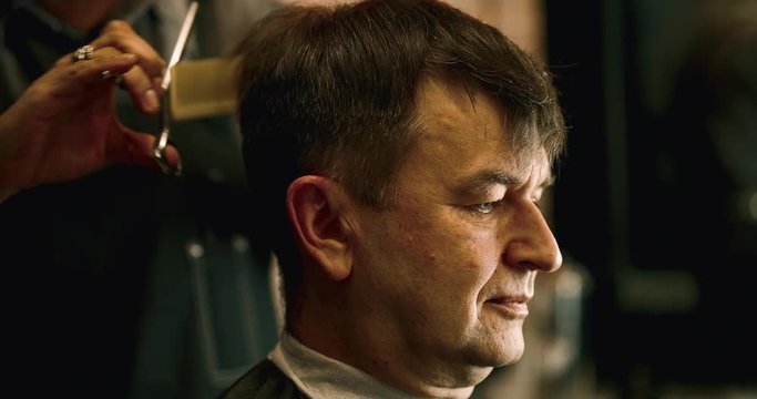 Old handsome Caucasian man getting a haircut in a modern barber shop. 4K Footage Raw edited. - Video