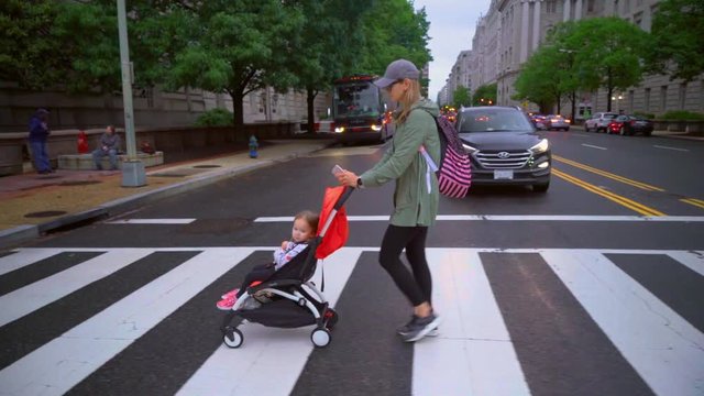 The girl with the stroller crosses the road. Evening in Washington DC.