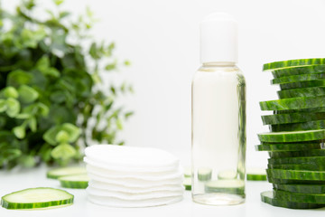 Fototapeta na wymiar Natural beauty remedy. Liquid skincare cosmetic in bottle, green cucumber slice, morning facial fresh cleanser tonic.