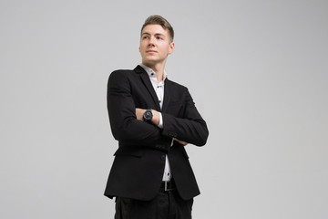 Portrait of young man in black suit with arms crossed isolated on white background