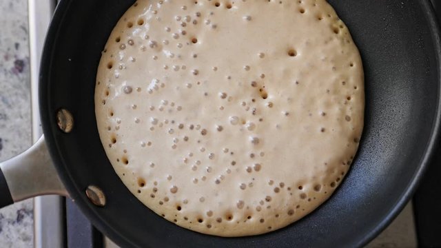Making home made pancakes on frying pan. Turning over flapjacks