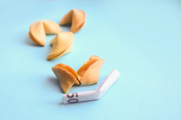 Euro banknote inside fortune cookies on blue background