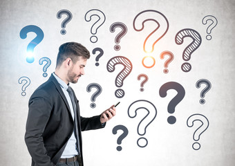 Businessman with phone, question marks