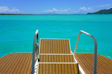 Jumping from the stairs of a boat onto the bright turquoise azure blue lagoon of Bora Bora in French Polynesia - obrazy, fototapety, plakaty