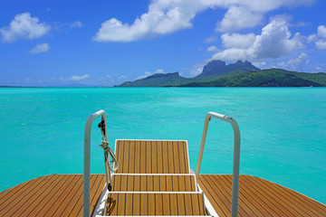 Jumping from the stairs of a boat onto the bright turquoise azure blue lagoon of Bora Bora in French Polynesia - obrazy, fototapety, plakaty