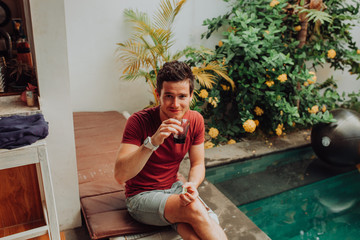 Fototapeta premium men eat crisps by swimming pool, man in swim pool with cocktails