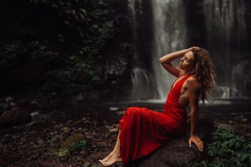 sexy young Girl in red dress at amazing Waterfall Bali - the best cascade in Indonesia