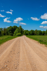 Fototapeta na wymiar country gravel road with old and broken asphalt