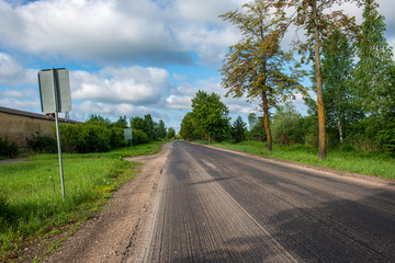 country gravel road with old and broken asphalt