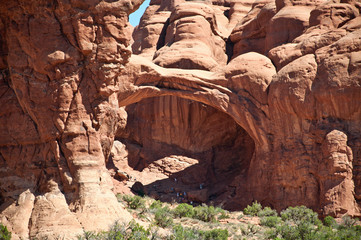 Tourists in the shade of an arch in Arches National Park