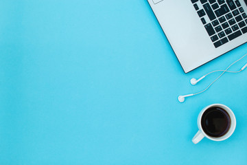 Laptop, headphones and coffee cup on a blue background.