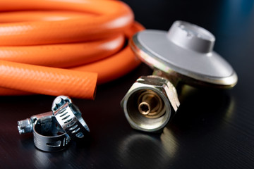 Regulator for propane-butane gas cylinder and accessories on a wooden workshop table. Gas...