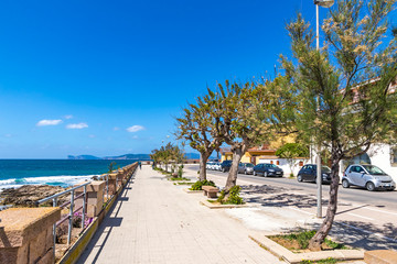 Fototapeta na wymiar Sunny view of sea promenade and the old walls of Alghero city, Sardinia, Italy. Mediterranean seacoast