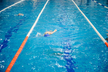 a 6-year boy swims backstroke in a swimming pool for competition