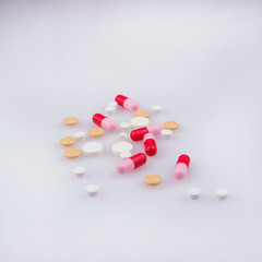 white and yellow pills, red-pink capsules on a white background