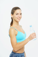 Attractive slim girl in sportswear with a smile opens a plastic bottle with clean water during a workout on a white background. 