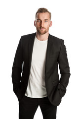 Handsome blonde man standing in front of a white background wearing a black blazer. Smiling looking at camera.