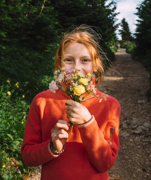 Portrait of redhead girl holding bunch of flower