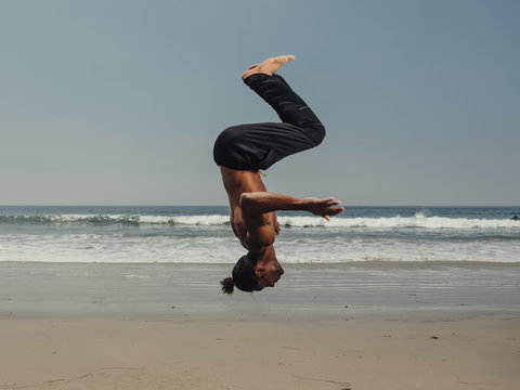 man acrobat backflip on beach