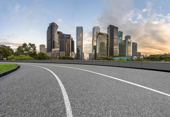 Fototapeta na wymiar curve asphalt road with city skyline background in china