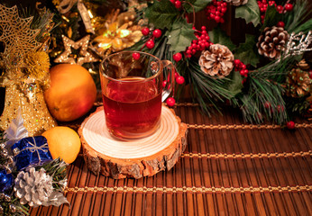 New Year and Christmas decor. Bottle with chocolate cookies and cups for tea stand on a table with green Christmas tree branches