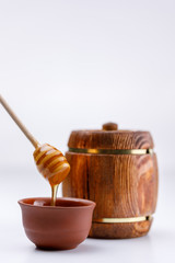 Isolated barrel and spoon for honey on a white background. Fragrant honey flowing from the stick.