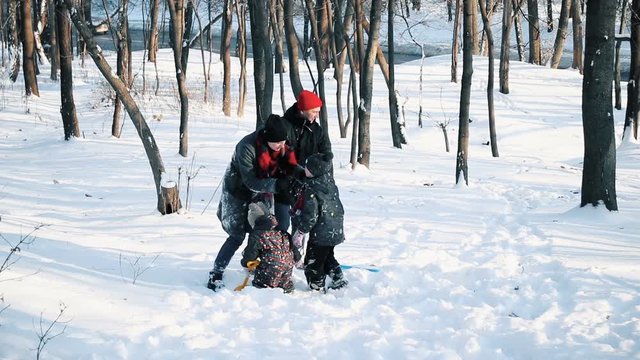 Mom and dad with their children on a walk in a winter snow-covered forest, they are happy and having fun, throwing snow.