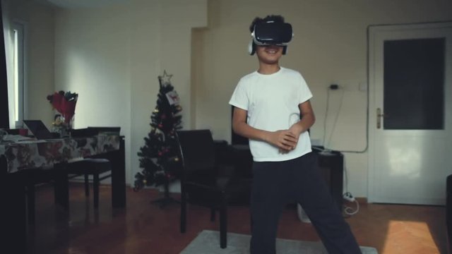 Сool african american boy wore VR goggles and hit the virtual reality. The child wore a virtual reality glasses. Fun for children at free time at home. Kids explore technical innovations. 