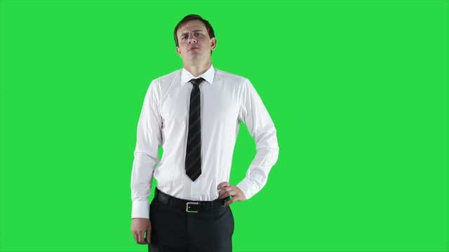 Portrait of young man in white shirt and tie. Confident businessman in white shirt looking displeased, a serious look on green background.
