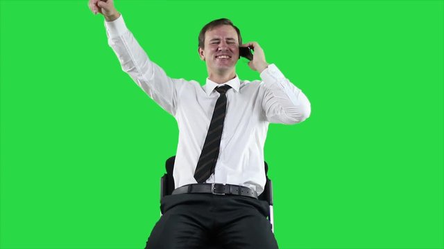 Successful business man on a green screen. Successful businessman emotionally speaks on the telephone. Businessman using smartphone. Cheerful entrepreneur speaking on mobile phone on green background.