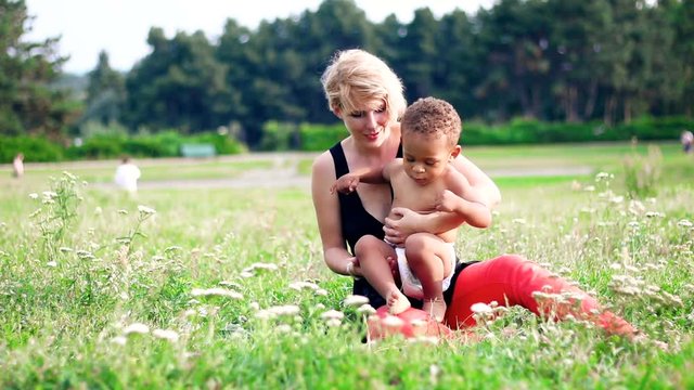Happy multiracial family. Young mother and her two years old little son for a walk in the park.