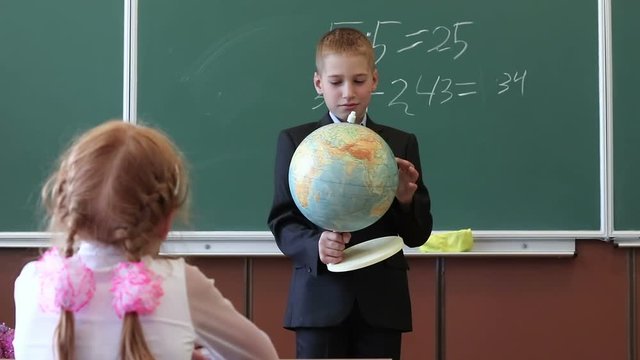 Children at elementary school. Children in geography lesson at school. Pupils view the globe in an elementary school class.