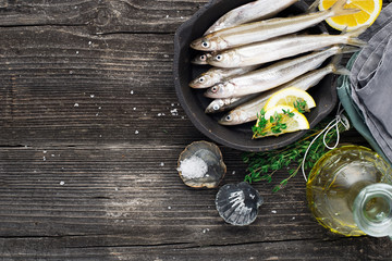 Fresh raw sea small fish smelt before cooking. Top view. On a dark background.