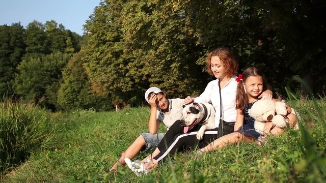Happy family in the park. Mother with her children and dog walking in summer forest. Mom and kids relaxing by the lake.