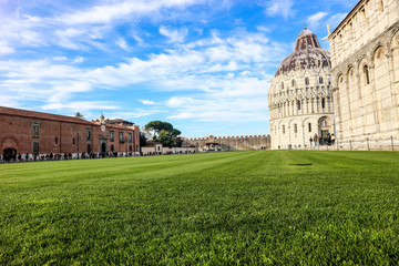 Green lawn at the piazza dei miracoli (square of miracles) with Pisa baptistery and cathedral, Tuscany, Italy