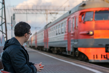 A man sitting on the platform against the background of standing next to the locomotive waiting