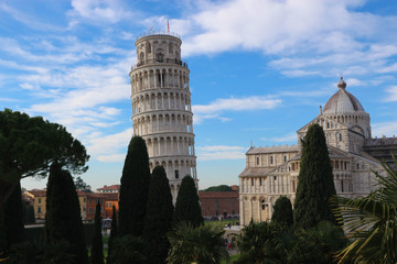 Amazing view from city wall to leaning tower of Pisa, symbol of Italy, and cathedral with green cypress and palm tree, Tuscany