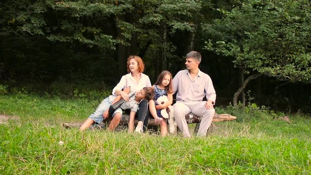 Happy family's on vacation in the park. Mother, father and their children and dog walking in summer forest.