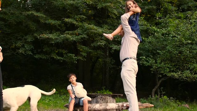 Family on a walk in summer forest. Dad and mom with their children and dog walking in summer forest. Happy family's on vacation in the park.