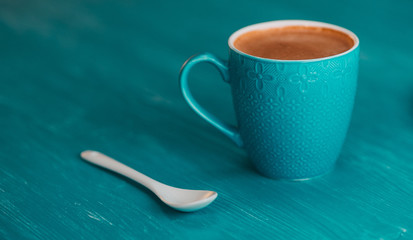 Coffee mug on a wooden turquoise background.