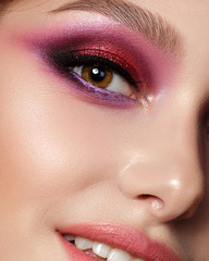 Closeup portrait of young beautiful woman with bright pink smokey eyes and lips. Fashion makeup. Studio shot. Modern summer make up. Extreme closeup, partial face view