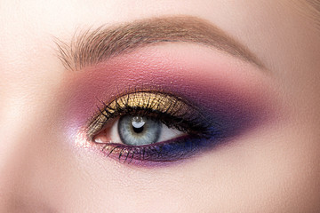 Close up of beautiful woman eye with multicolored smokey eyes makeup. Modern fashion make up. Studio shot