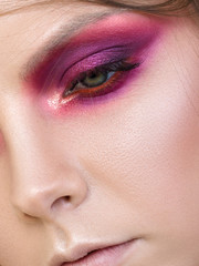 Close up beauty portrait of young woman with purple smokey eyes. Perfect skin and fashion makeup. Studio shot. Sensuality, passion, trendy youth makeup concept. Extreme closeup, partial face view
