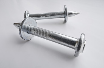 The isolated object is a shiny and new dowel-nails for concrete on a light background. Metal, hardware, fasteners.