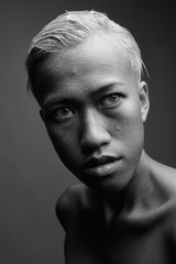 Young beautiful rebellious woman with short hair against gray ba