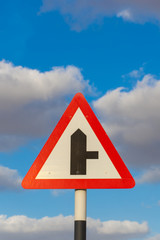 Fork in the road roadsign with a blue sky and cloudy background.