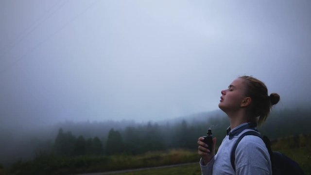 girl uses vape in a misty forest